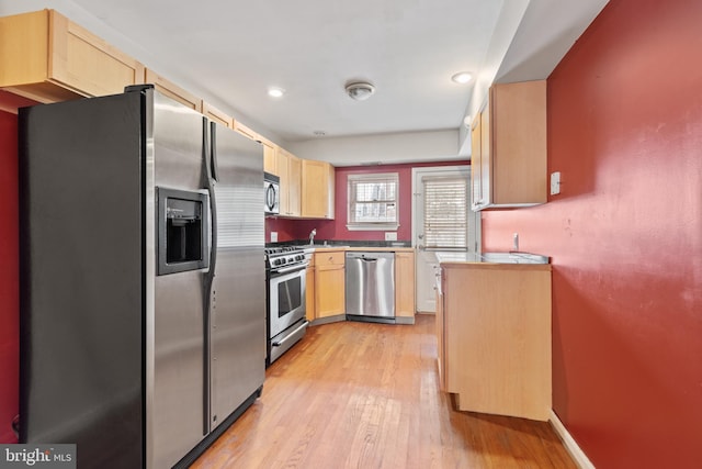 kitchen with sink, light wood-type flooring, light brown cabinets, and appliances with stainless steel finishes