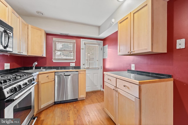 kitchen featuring light wood-type flooring, tile countertops, appliances with stainless steel finishes, light brown cabinetry, and sink