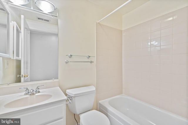 full bathroom featuring vanity, tiled shower / bath, and toilet