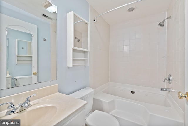 full bathroom featuring tiled shower / bath, vanity, and toilet