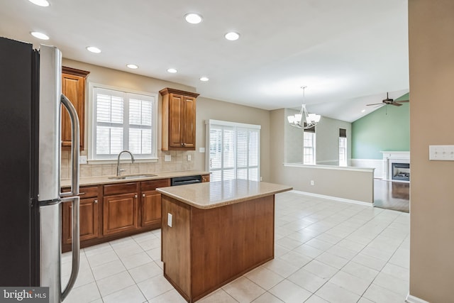 kitchen featuring sink, stainless steel refrigerator, a center island, tasteful backsplash, and vaulted ceiling