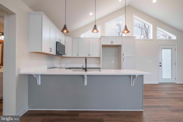 kitchen with white cabinets, light countertops, decorative light fixtures, and a kitchen bar