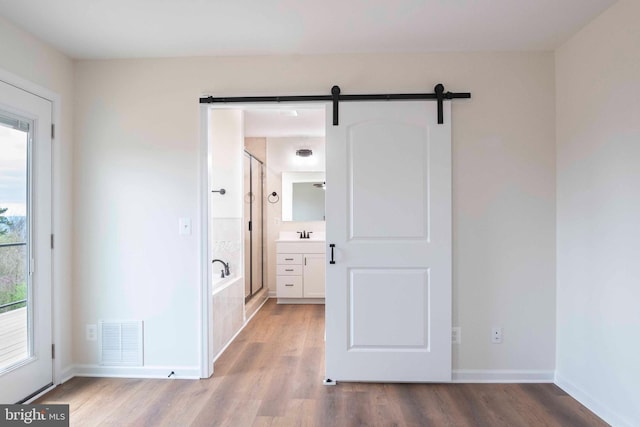 interior space featuring baseboards, a barn door, visible vents, and wood finished floors