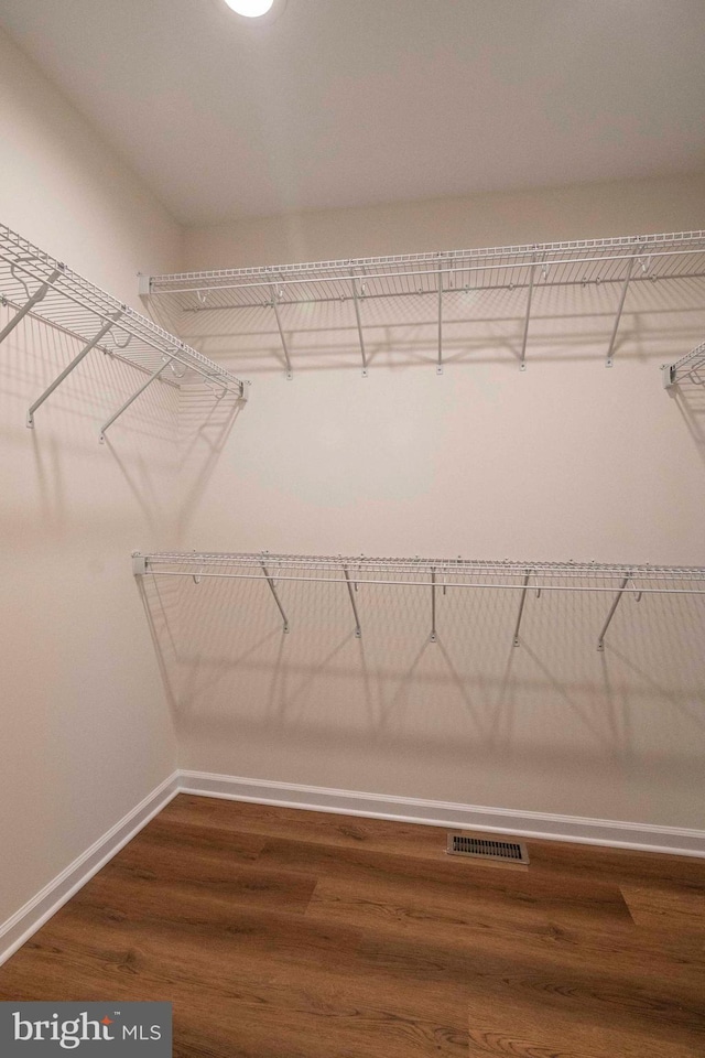 walk in closet with dark wood finished floors and visible vents