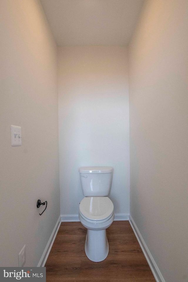 bathroom with toilet, baseboards, and wood finished floors