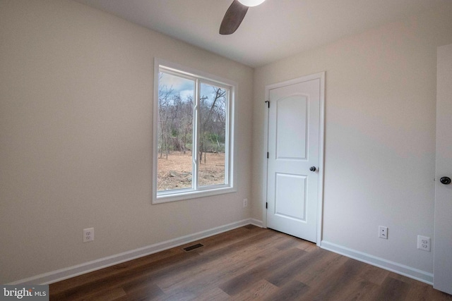 unfurnished room with a ceiling fan, dark wood finished floors, visible vents, and baseboards