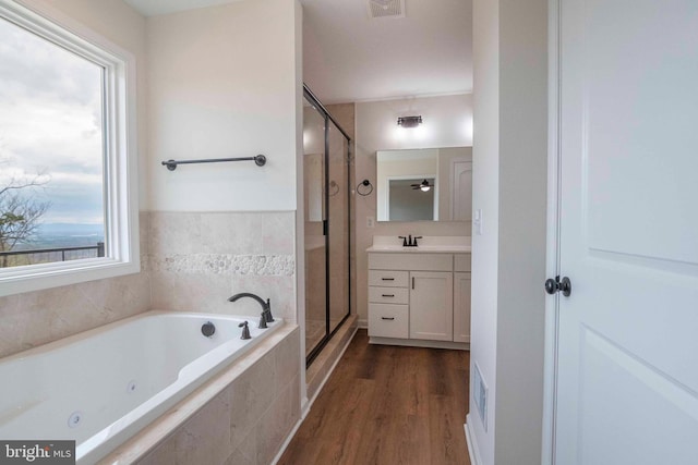 bathroom with a jetted tub, a shower stall, wood finished floors, and vanity