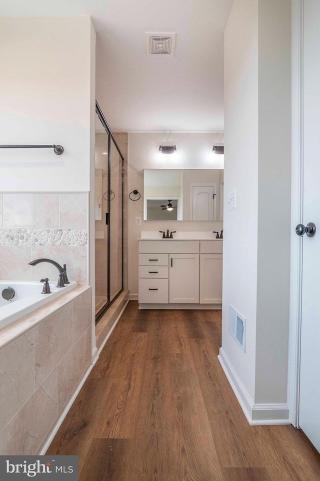 full bath featuring a garden tub, wood finished floors, a shower stall, and visible vents