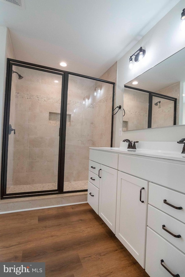 full bathroom with visible vents, wood finished floors, vanity, a shower stall, and recessed lighting