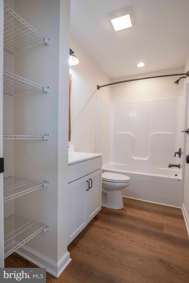 full bath with baseboards, toilet, wood finished floors, tub / shower combination, and vanity