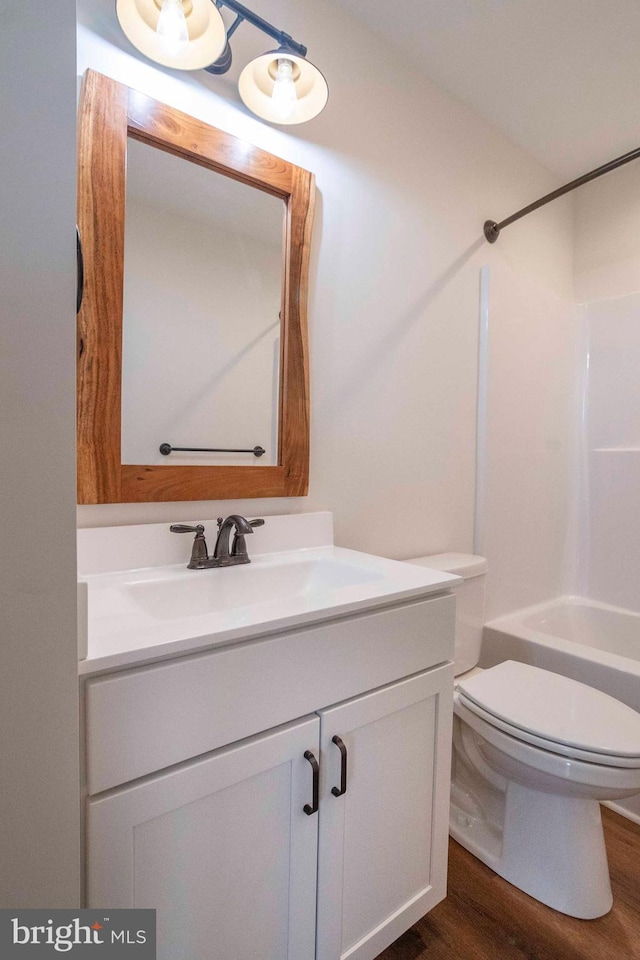 full bath with toilet, shower / tub combination, wood finished floors, and vanity