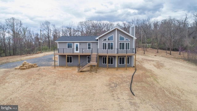 chalet / cabin featuring stairs, driveway, a chimney, and a wooden deck