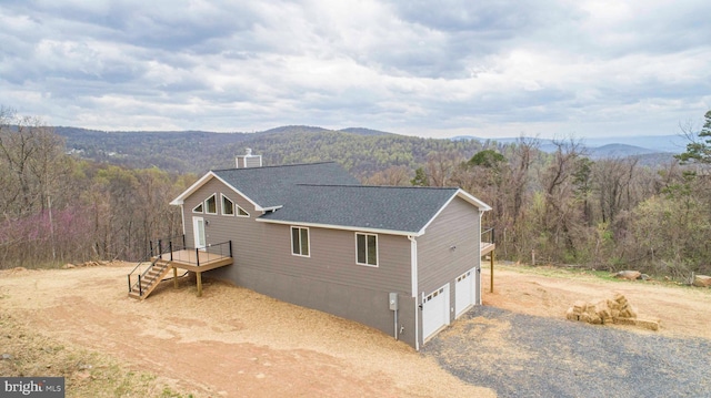 view of front of house featuring a garage, a mountain view, a wooded view, and stairs