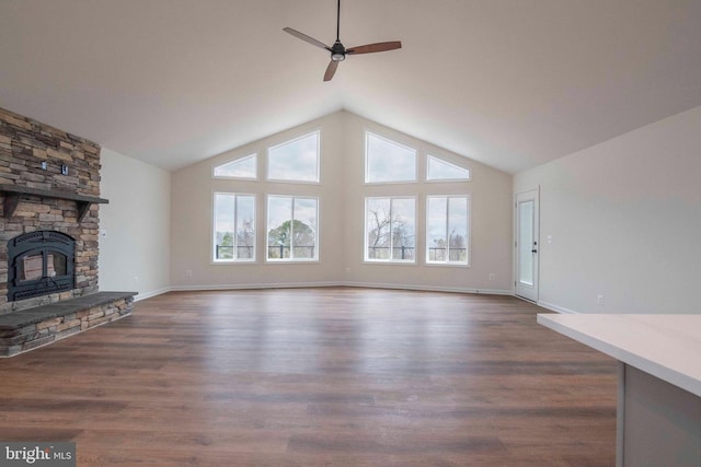 unfurnished living room featuring baseboards, dark wood-style floors, ceiling fan, a fireplace, and high vaulted ceiling