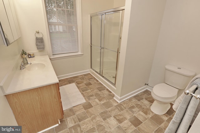 bathroom featuring toilet, vanity, and a shower with door