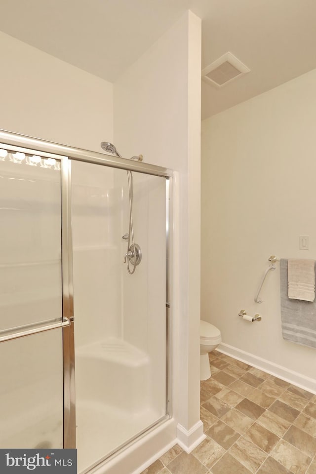 bathroom featuring toilet and a shower with shower door