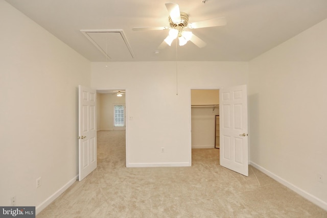 unfurnished bedroom featuring light carpet, a spacious closet, ceiling fan, and a closet