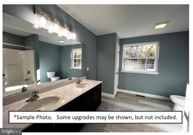 full bathroom with vanity, a healthy amount of sunlight, washtub / shower combination, and toilet