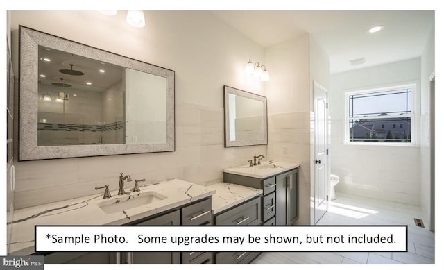 bathroom featuring vanity, tiled shower, tile walls, and toilet