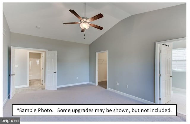 unfurnished bedroom with lofted ceiling, a walk in closet, light colored carpet, a closet, and ceiling fan