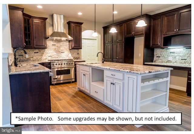 kitchen featuring pendant lighting, wall chimney range hood, stainless steel stove, and decorative backsplash