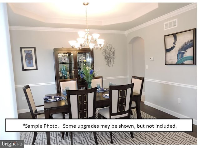 dining space featuring a tray ceiling, ornamental molding, and a chandelier