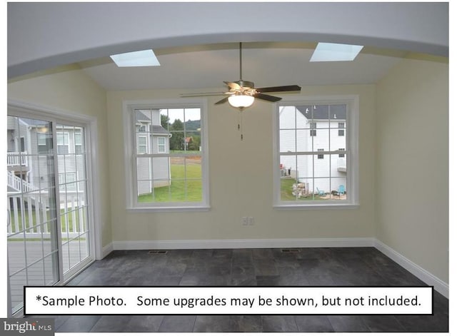 unfurnished room with ceiling fan and vaulted ceiling with skylight