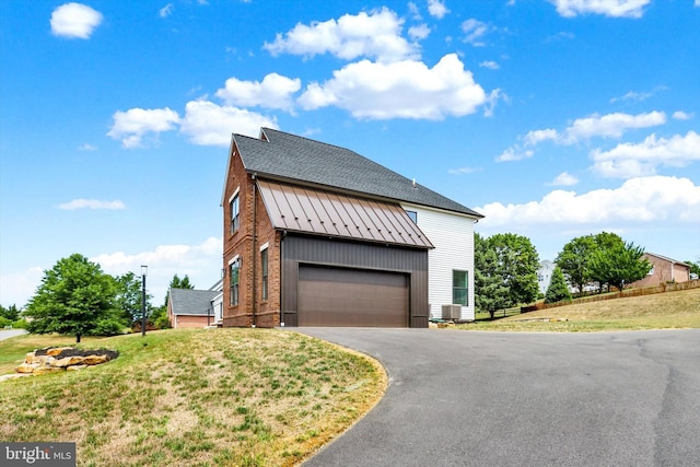 view of front facade featuring a garage, a front yard, and central AC unit