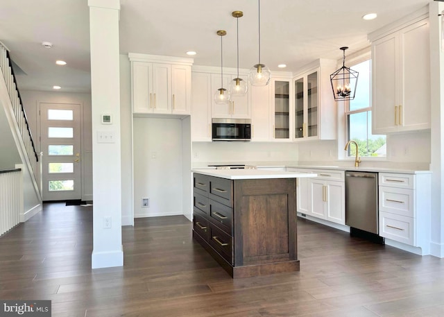 kitchen featuring white cabinetry, a center island, hanging light fixtures, appliances with stainless steel finishes, and dark hardwood / wood-style floors