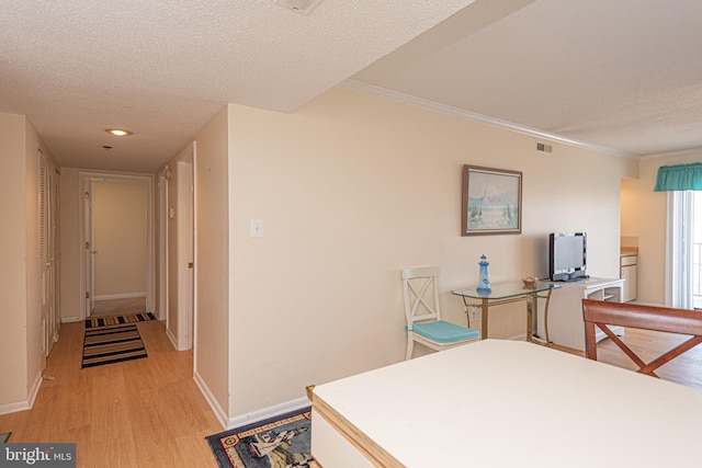 interior space with ornamental molding, a textured ceiling, and light hardwood / wood-style flooring