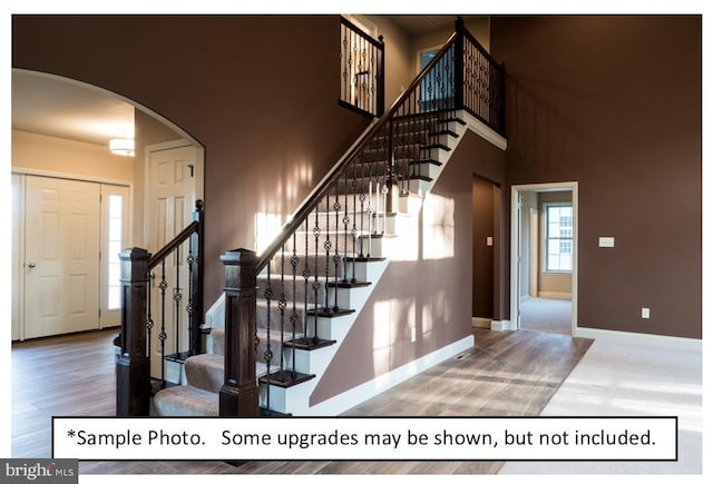 stairs with a high ceiling and wood-type flooring