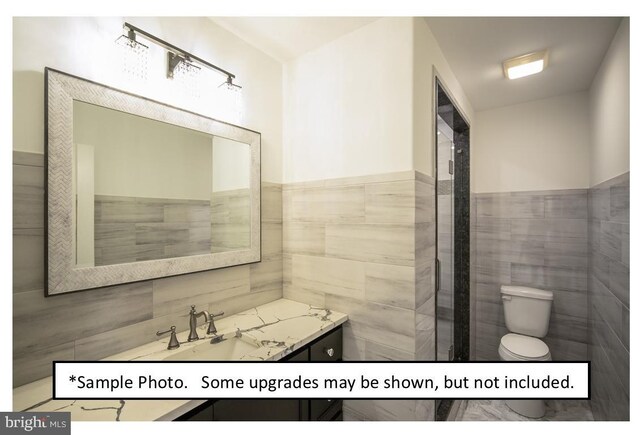 bathroom with tile walls, toilet, and vanity