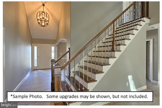 foyer entrance with wood-type flooring, a towering ceiling, and a chandelier