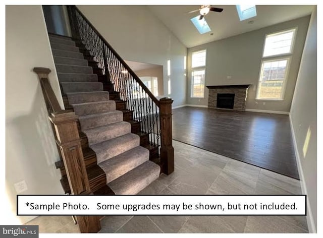 stairs with a skylight, wood-type flooring, high vaulted ceiling, and ceiling fan