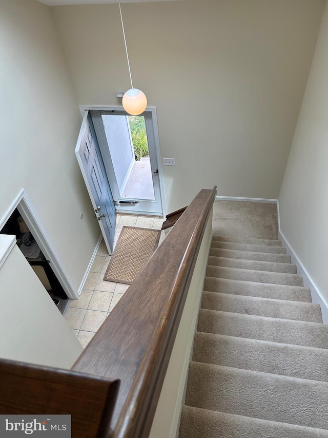 stairs with light tile patterned flooring and a towering ceiling