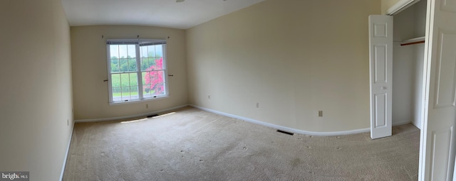 unfurnished bedroom featuring light colored carpet and vaulted ceiling