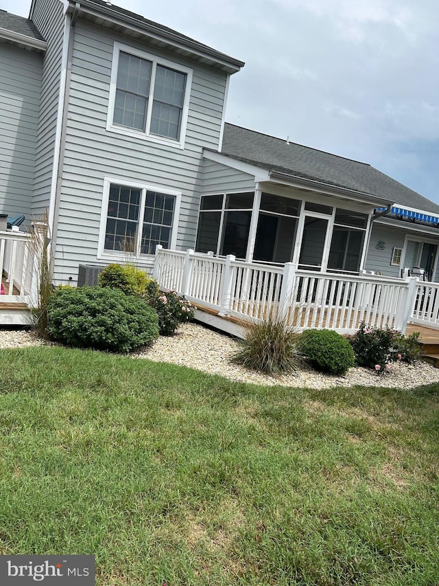 rear view of house featuring a lawn and a wooden deck