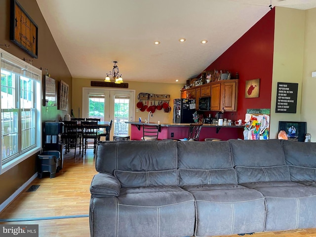 living room featuring sink, light hardwood / wood-style floors, vaulted ceiling, and a wealth of natural light