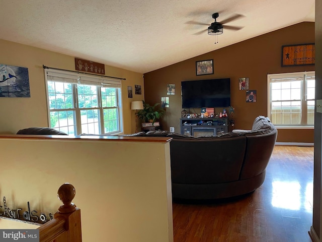 living room featuring vaulted ceiling, wood-type flooring, ceiling fan, and a textured ceiling