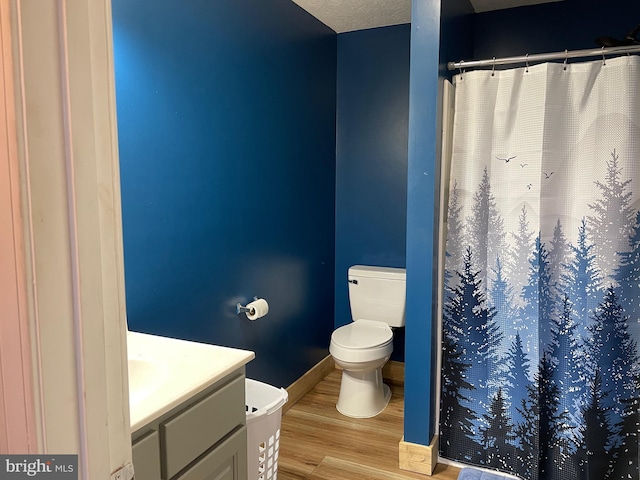 bathroom with hardwood / wood-style floors, vanity, a textured ceiling, a shower with curtain, and toilet