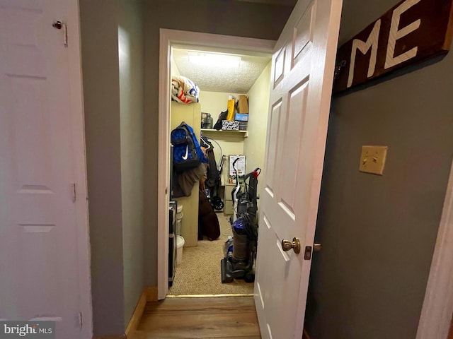 hallway with hardwood / wood-style floors and a textured ceiling