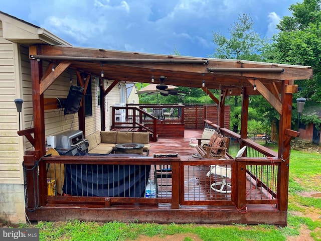 wooden deck with ceiling fan and a fire pit