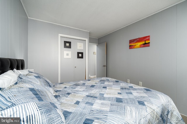 bedroom featuring crown molding, wooden walls, and a closet