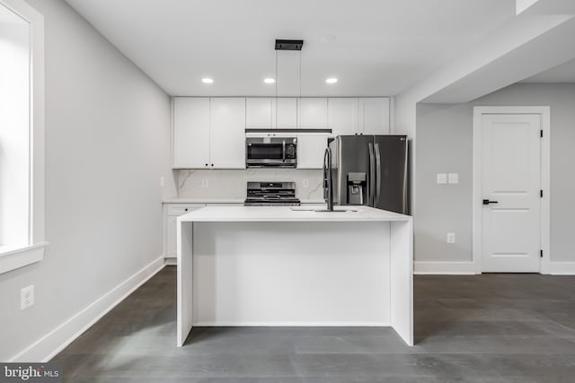 kitchen with stainless steel appliances, a center island with sink, dark hardwood / wood-style floors, and hanging light fixtures