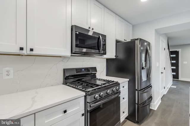 kitchen with wood-type flooring, light stone countertops, tasteful backsplash, white cabinetry, and stainless steel appliances