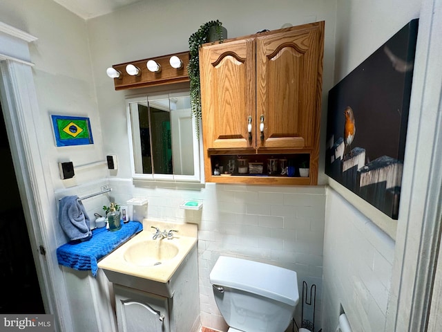 bathroom with tasteful backsplash, toilet, vanity, and tile walls