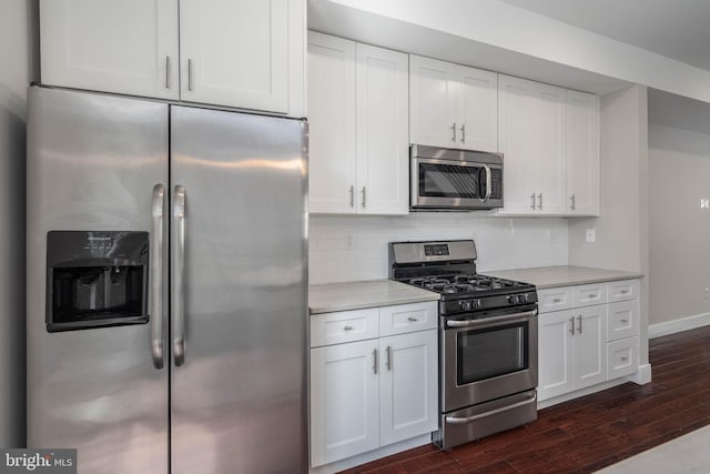 kitchen with stainless steel appliances, light stone counters, decorative backsplash, white cabinetry, and dark wood-type flooring