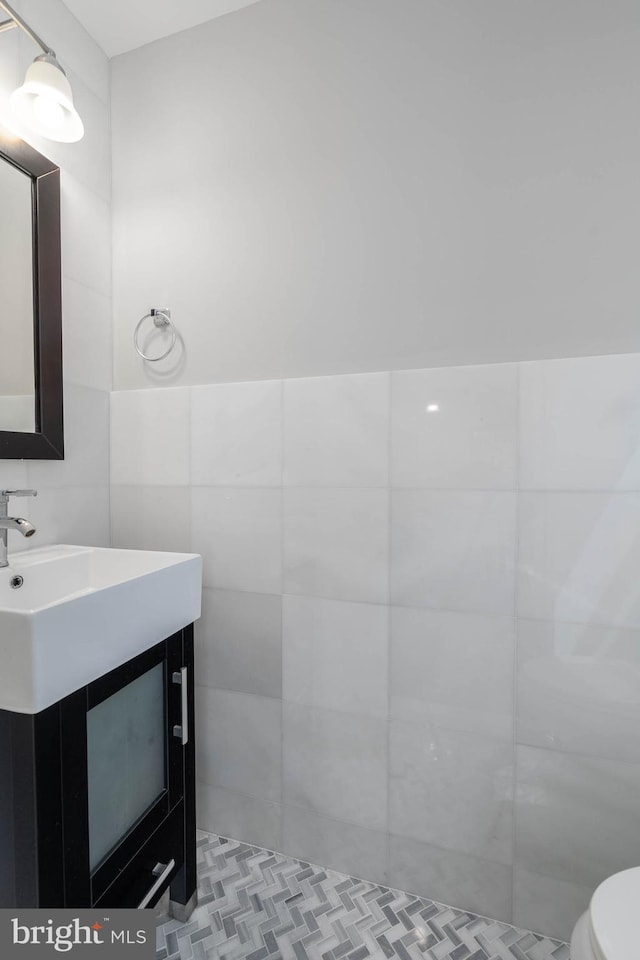 bathroom featuring vanity, toilet, and tile walls