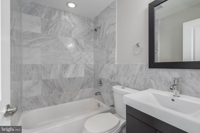 full bathroom with tile walls, vanity, toilet, and tiled shower / bath