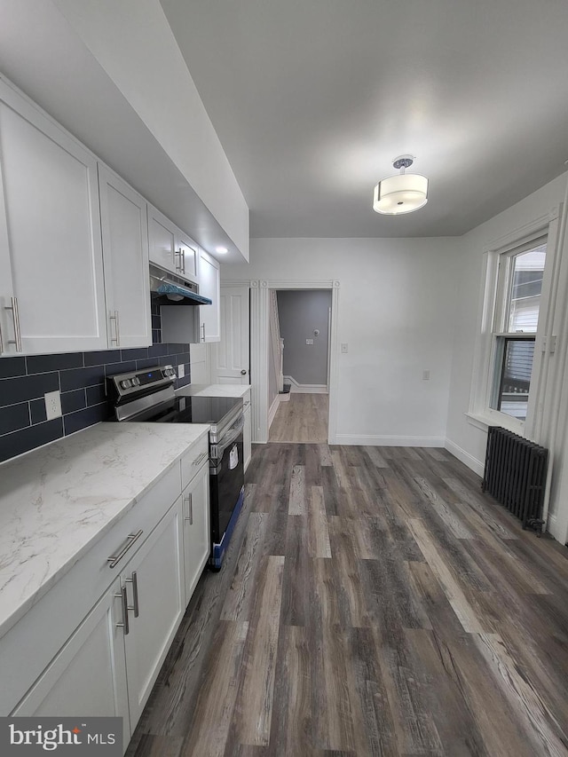 kitchen featuring white cabinetry, radiator heating unit, light stone counters, decorative backsplash, and stainless steel range with electric cooktop